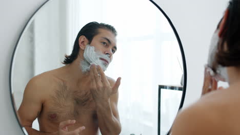 man shaving in front of mirror