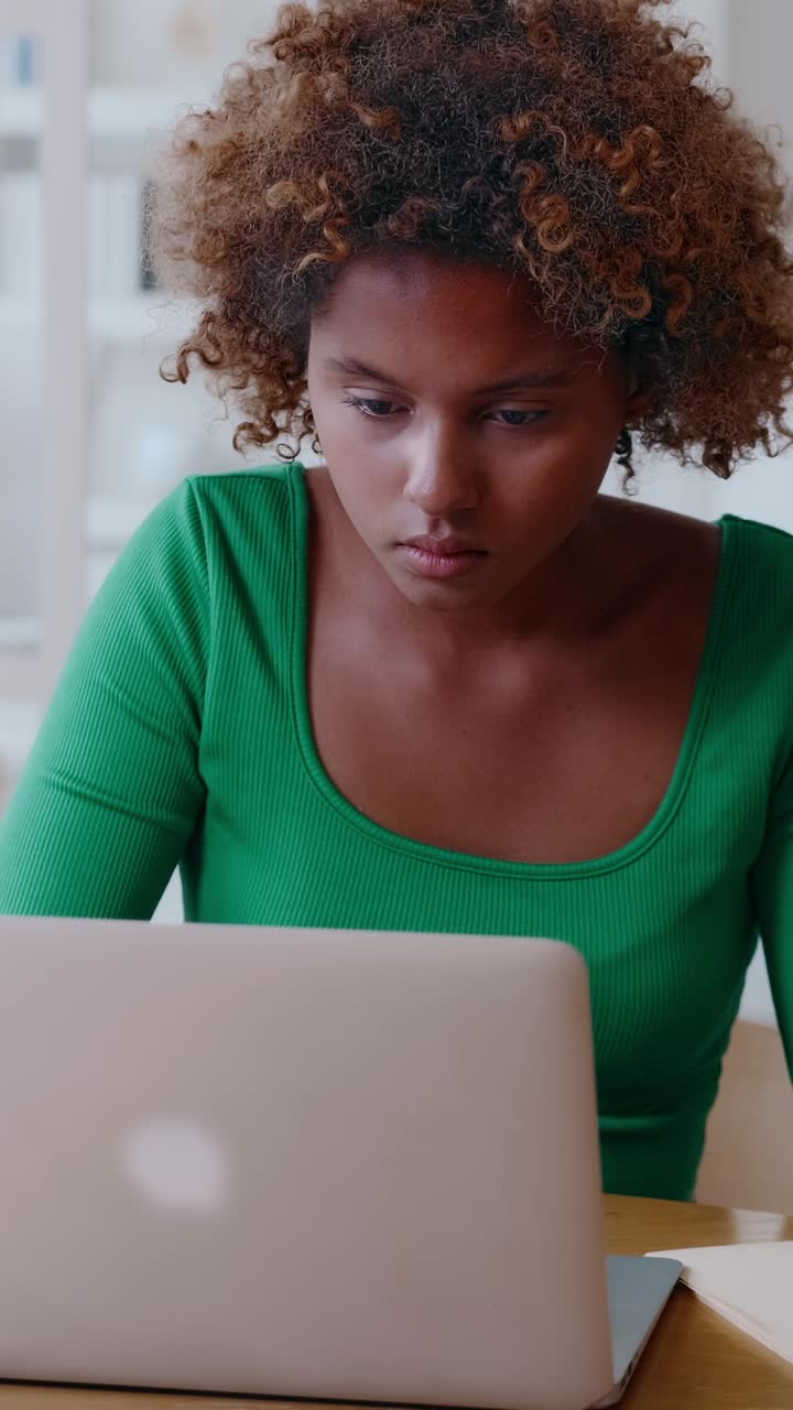 Focused young woman working on laptop at home office concentrating on screen