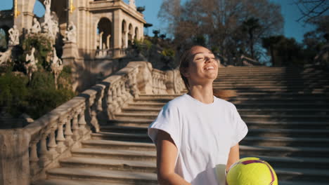 una mujer caucásica haciendo trucos de fútbol en la ciudad.