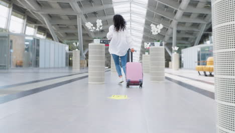 woman with luggage walking through an airport terminal