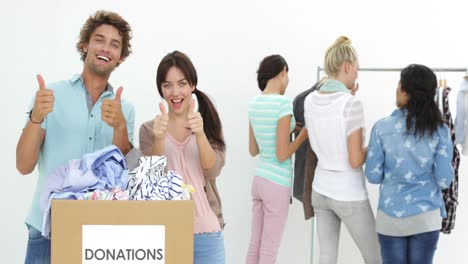 team of happy workers going through donation box of clothes