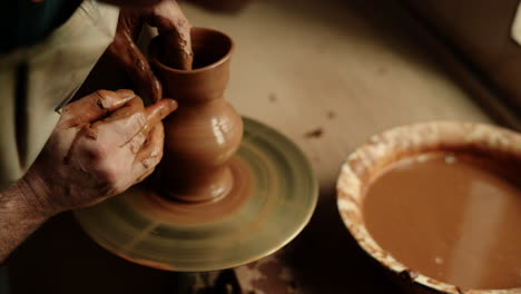 ceramist producing clay jar in pottery. unrecognized man working with wet clay