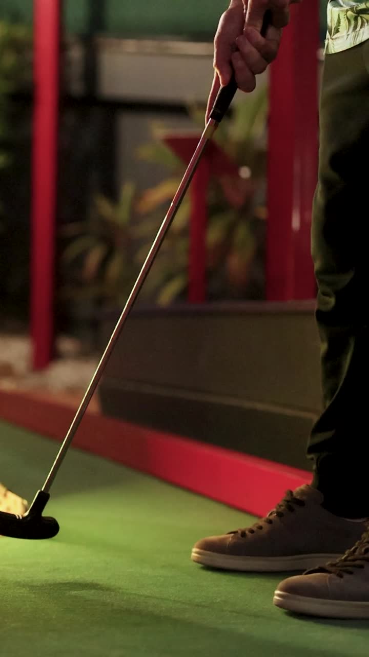 A player attempts a mini golf putt at a glowing ramp under warm lighting, capturing the essence of fun and challenge