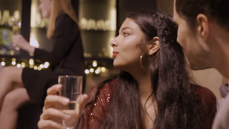 close up view of a couple celebrating the new year's party with friends, they are sitting at a table while eating grapes and drinking champagne with great complicity