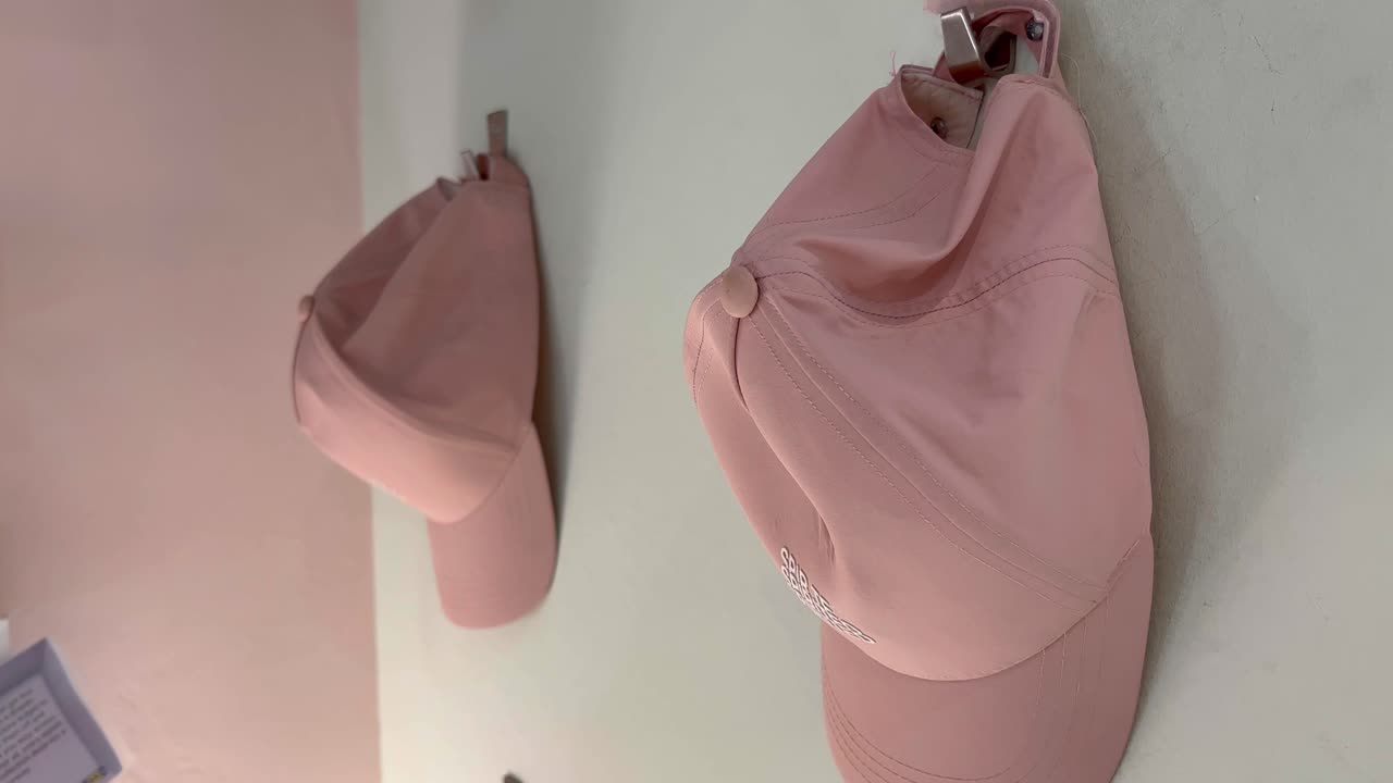 Due cappelli rosa o color pesca appesi al gancio nel negozio al dettaglio esposti per la vendita