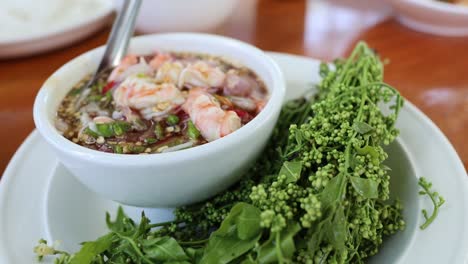 mixing a fresh shrimp salad with herbs