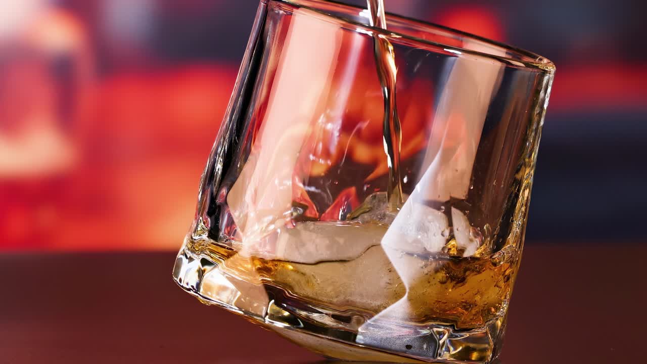 whisky siendo vertido en un vaso con hielo