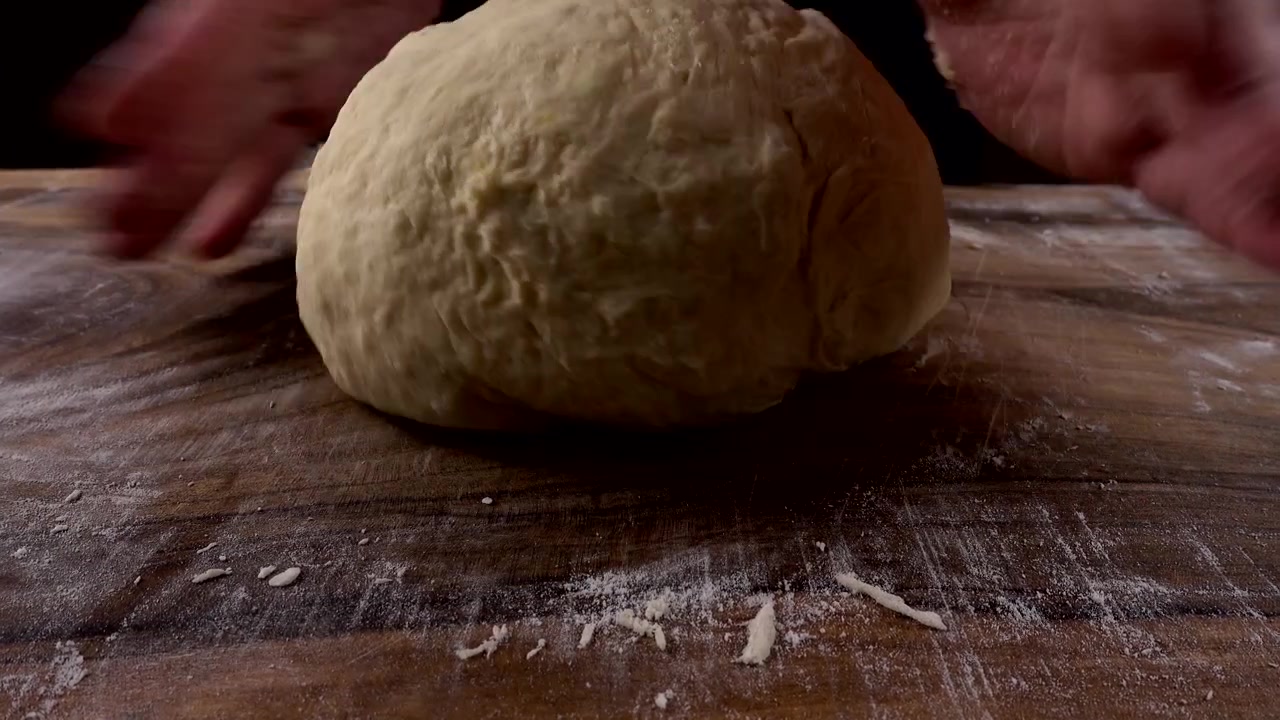 Impastare la pasta su un tagliere di legno con le mani