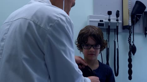 rear view of young asian male doctor examining caucasian boy patient chest in a clinic 4k