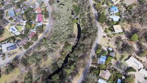 drone aerial following a river system with a trail in a suburban town