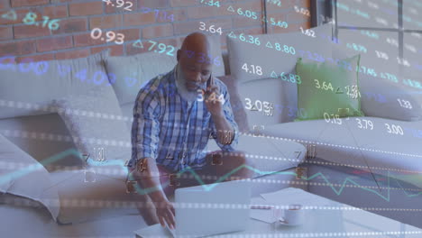 animation of trading board over senior african american man talking on cellphone while using laptop