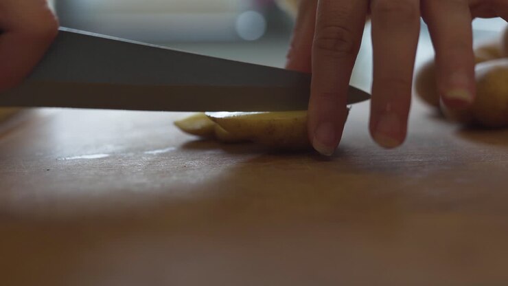 Una donna in cucina che dispone pezzi di carote e patate su una teglia da forno, pronti per essere infornati-2.
