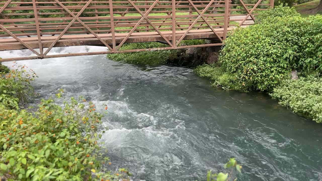 agua moviéndose rápido debajo de un pequeño puente de primavera