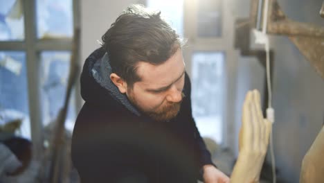 bearded artist making sculpture of buddha at workshop studio