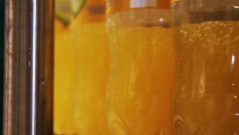 Close-up-bottles-being-filled-with-juice-on-production-line