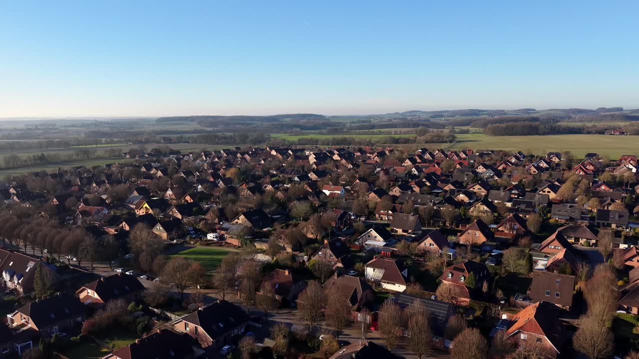 Amerikanische Vorstadtsiedlung in ländlicher Gegend mit Feldern im Hintergrund. Sonniger Tag mit blauem Himmel in der Wintersaison. Rote Backsteinhäuser der Vororte in den USA. Weite Luftaufnahme