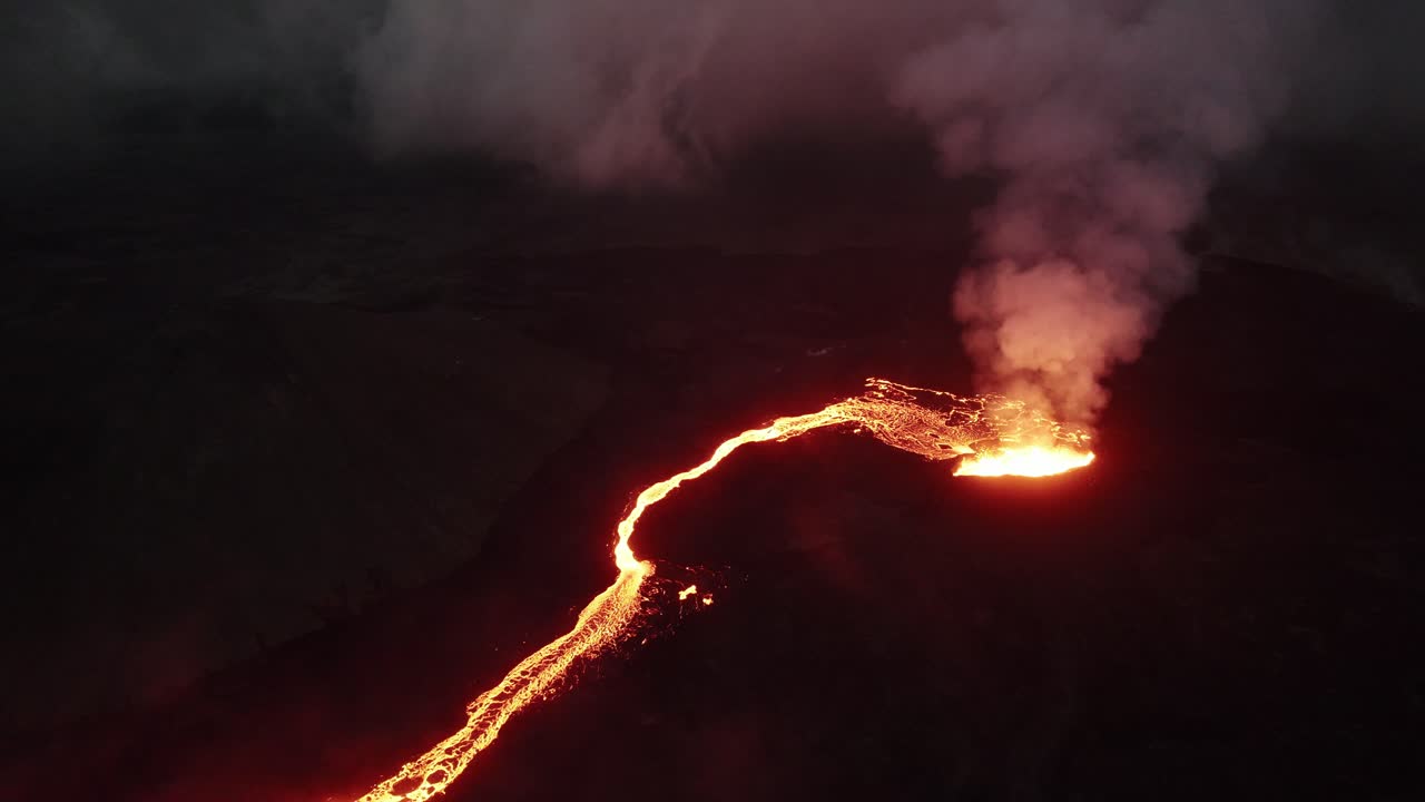 pull back high angle drone shot of the litli hrutur volcano in iceland with fog and smoke