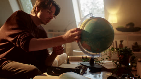Man studying a globe in a cozy attic room