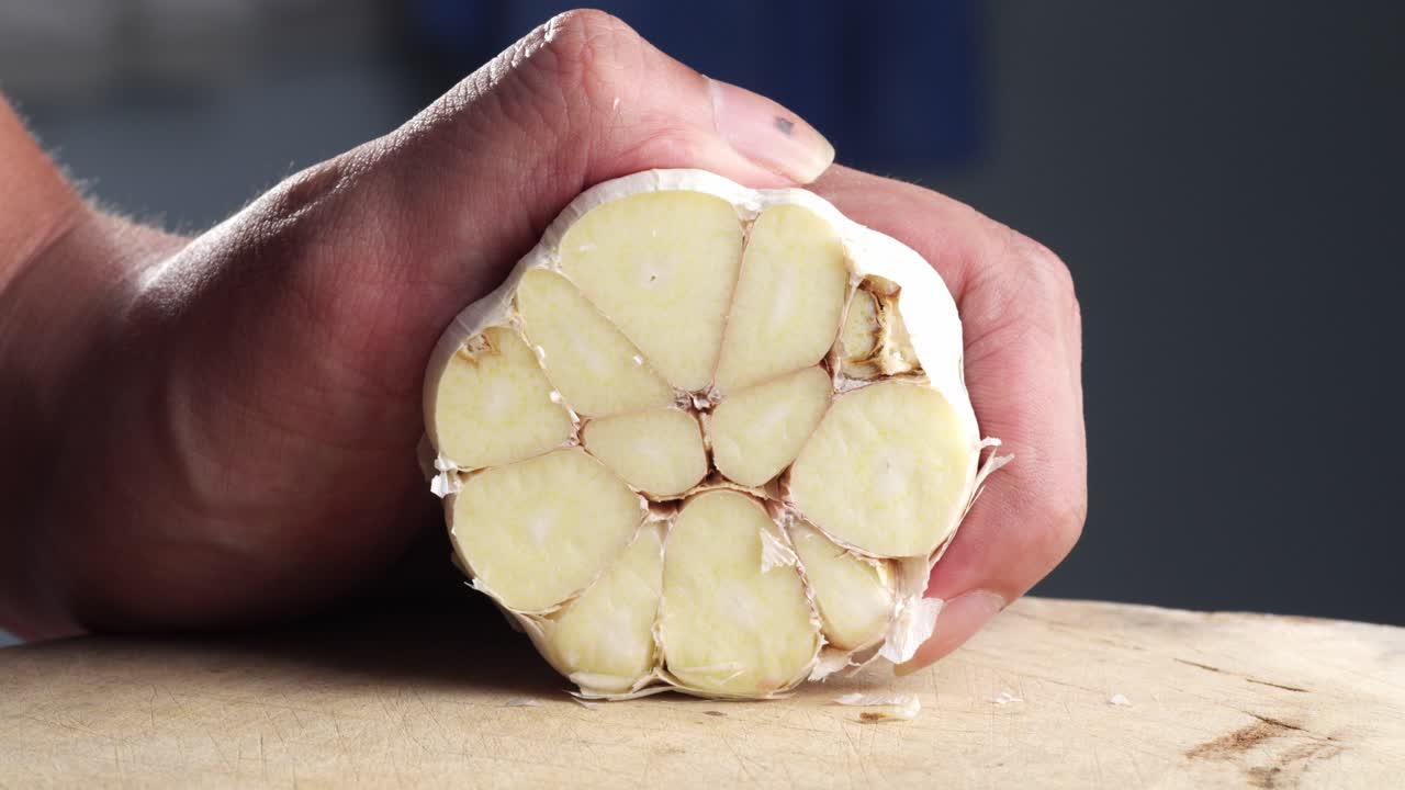 Close-up of a hand holding fresh garlic on a cutting board