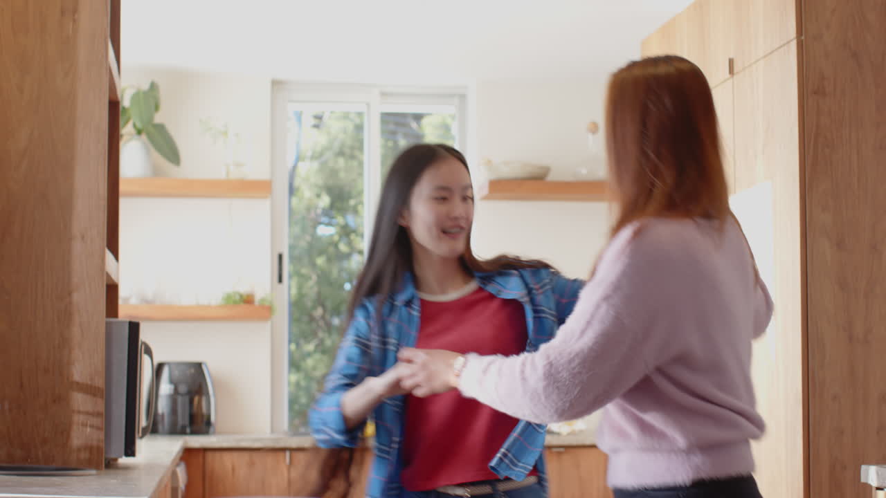 Dancing together, asian mother and daughter enjoying quality time in kitchen