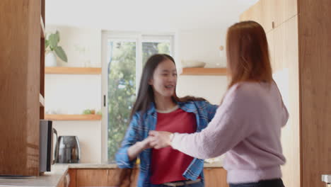 dancing together, asian mother and daughter enjoying quality time in kitchen