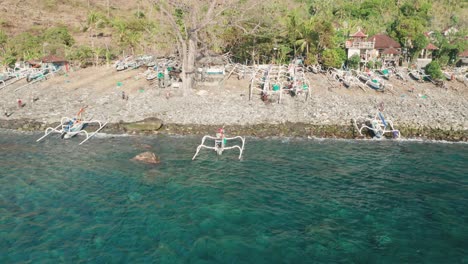 Traditional-jukung-outrigger-fishing-boat-returning-to-shore-of-Bali,-aerial