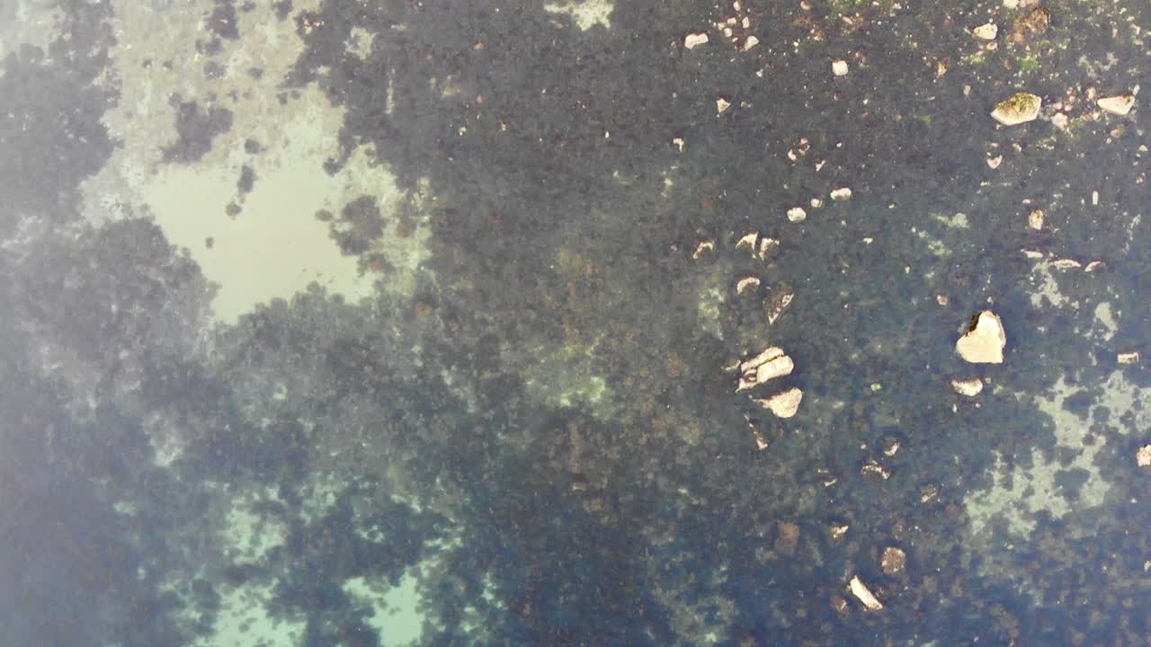 Aerial downward forward view of clear waters and rock pools in Devon England
