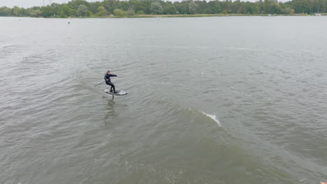 two hydro foil surfers surfing wave behind boat on river in germany