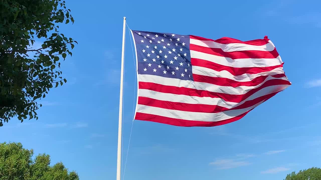 American Flag waving in the wind against blue sky.