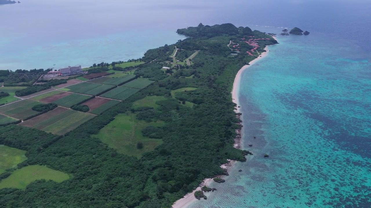 Japonya, Okinawa, Ishigaki Adası'ndaki Kabira Koyu, Club Med ve Tabaga Plajı boyunca sağa doğru ilerlerken sola doğru kaydırılan yatay hava çekimi.