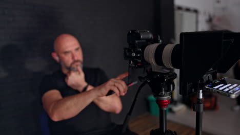 male caucasian photographer sits looking at the display of camera. portrait of a cameraman working in studio.