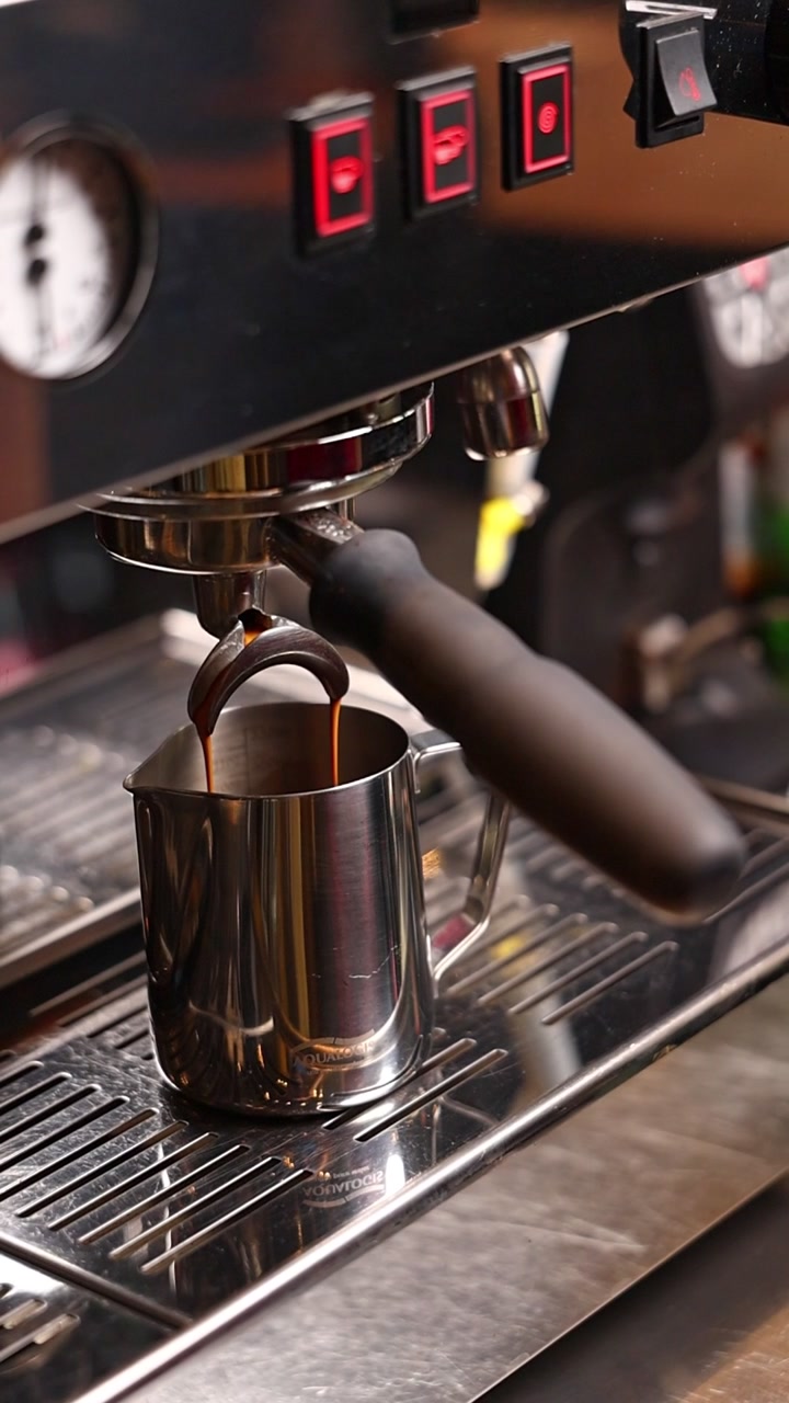 Espresso che viene erogato da macchina da caffè professionale in una brocca di metallo