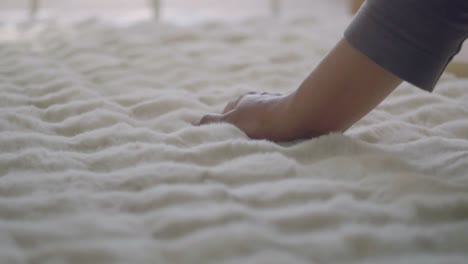 hand touching a white faux fur blanket