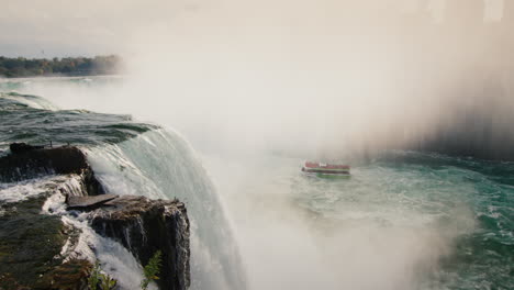 las famosas cataratas del niágara son un punto de referencia del estado de nueva york y américa. en la distancia en el río flota un barco con turistas
