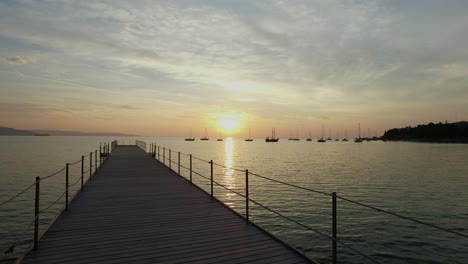 Drone-Volando-Bajo-Sobre-Un-Muelle-Hacia-La-Hermosa-Puesta-De-Sol-Sobre-El-Lago