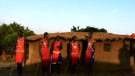 medium shot of five maasai warriors dancing at a village near masai mara