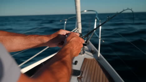 Hands Holding a Fishing Rod on a Sailboat