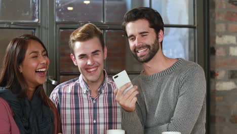 Smiling-hipster-friends-discussing-over-a-smartphone