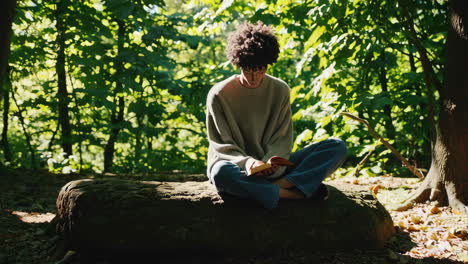 a young person reading a book outdoors in nature