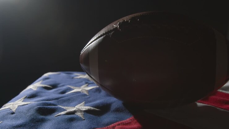 low-key-beleuchtung, studioaufnahme des american football auf der flagge der stars and stripes