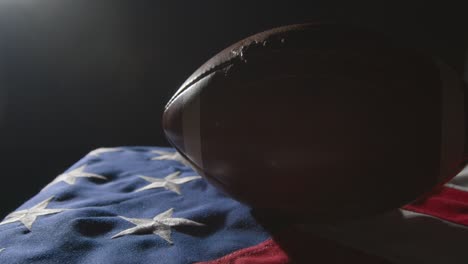 low key lighting studio shot of american football on stars and stripes flag