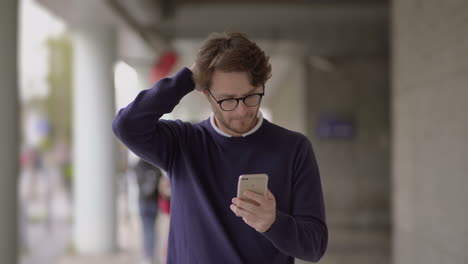 thoughtful man using smartphone outdoor