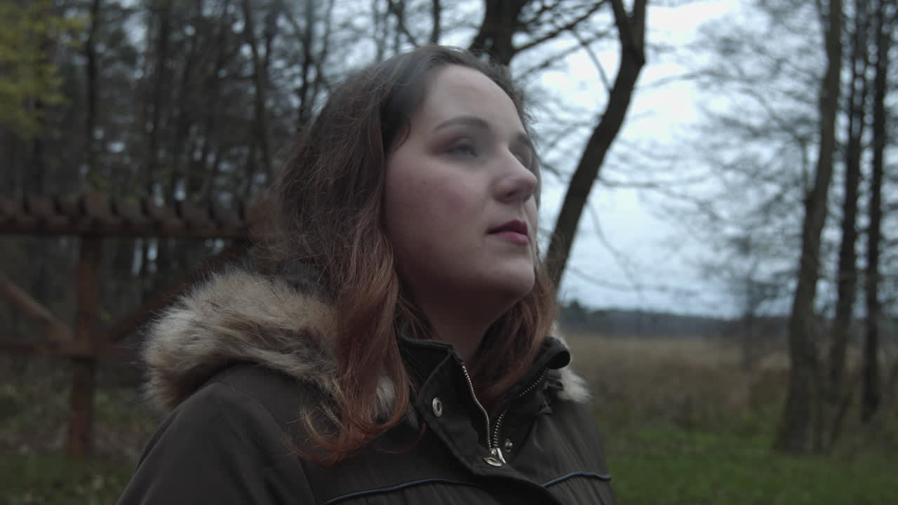 A woman who smoke cigarette, having solitude time in the woodland thinking of older fantasy and laugh