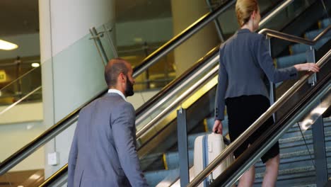 hombre de negocios y mujer subiendo la escalera con equipaje