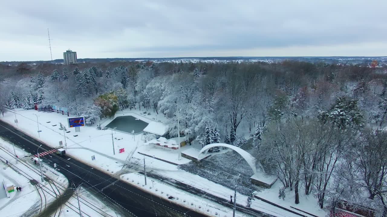 Transport road in the city near the big park. Snowy urban panorama in winter season. Aerial view.