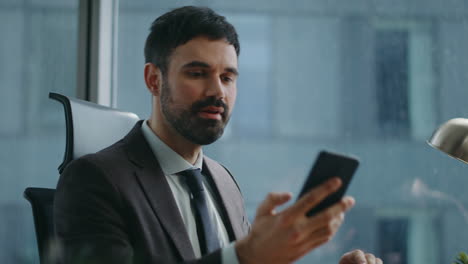 busy employee watching phone after typing laptop sitting luxury office close up.