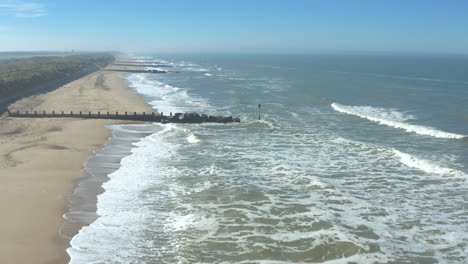 Low aerial shot Horsey Gap sandy beach, the agitated sea and powerful white foam waves