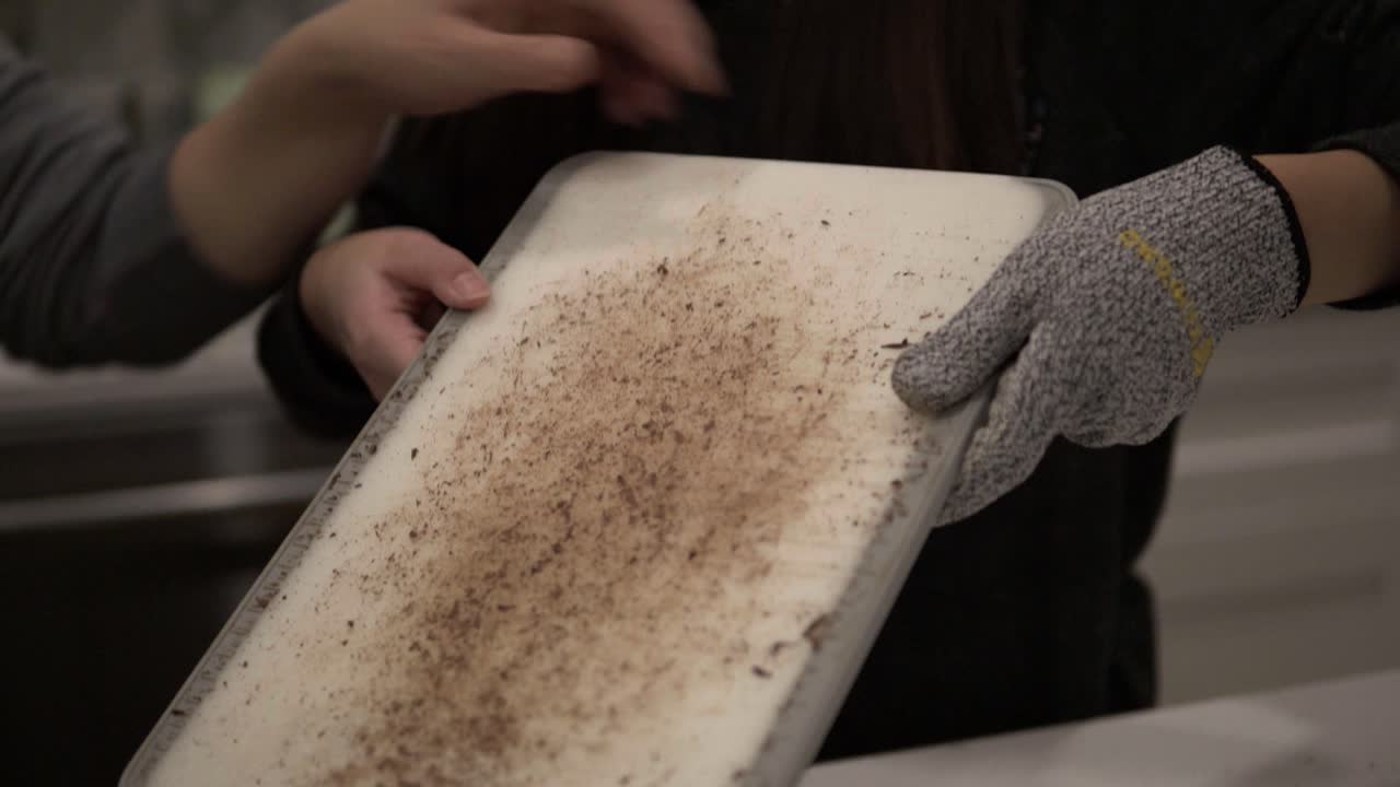 안전장갑을 끼고 백만장자 쇼트브레드 쿠키를 만들기 위해 녹이기 전에 다크 초콜릿을 자르는 젊은 한국 소녀-2