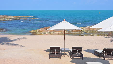 Lounge-Chairs-and-Parasols-on-Tropical-Beach-with-Blue-Ocean