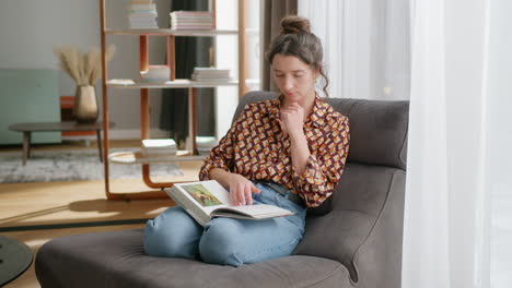 mujer caucásica descansando en una silla cómodamente leyendo un libro